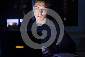 Man is working on a laptop at night.