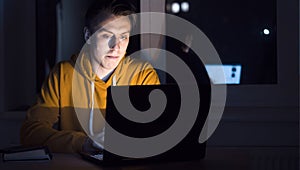 Man is working on a laptop at night.