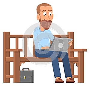 Man working on laptop outdoor. Guy sitting on park bench