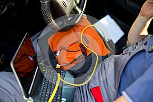 Man working on laptop while sitting in a car in workshop, close