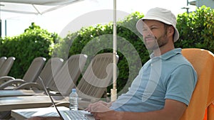 Man working on laptop on a sun lounger