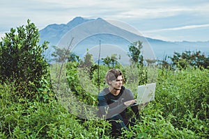 Man working with laptop on the top of mountain with beautiful la