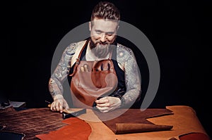 Man working with leather cutting out leather shapes for a new product in his tanning shop
