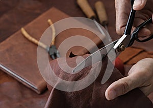 Man working with leather using scissors.