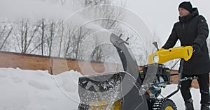 Man working with manual snow blower. Snowy winter. Man removes snow snowdrifts with Snowplough. Snowblower in action