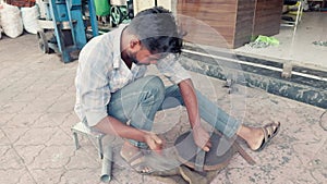 Man working on metal with tools on a street showcasing traditional craftsmanship