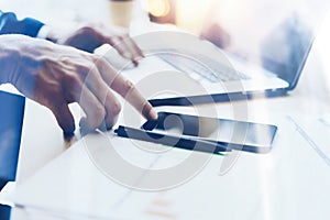 Man working on modern mobile phone at office and pointing finger to home button.Horizontal closeup view, blurred