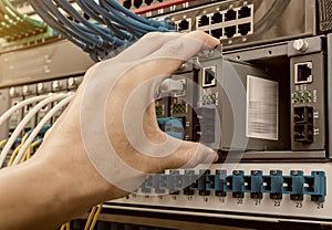 Man working in network server room with fiber optic hub