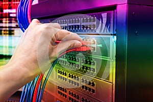 Man working in network server room with fiber optic hub