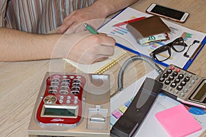 Man working on office desk with Calculator, a computer, a pen and document. Man, counting money and making calculations
