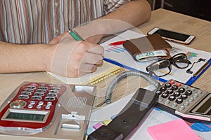 Man working on office desk with Calculator, a computer, a pen and document. Man, counting money and making calculations