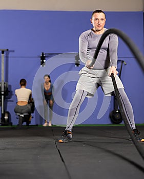 Man working out with battle ropes at crossfit gym