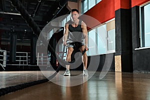 Man working out with battle ropes in gym