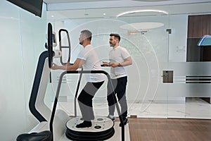 Man working out on modern rehab equipment supervised by professional