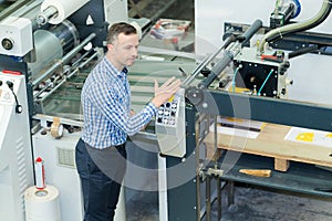 man working with paper sheets feeling into printing machine