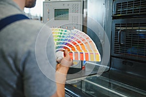 Man working in printing house with paper and paints