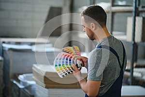 Man working in printing house with paper and paints