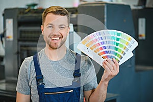 Man working in printing house with paper and paints