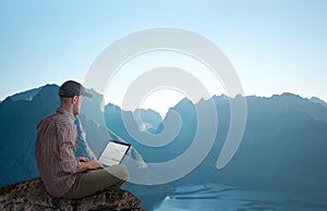 Man working remotely outdoors with laptop photo