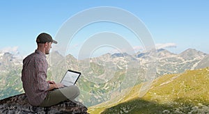 Man working remotely outdoors with laptop photo