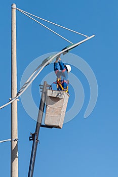 Man working replacing bulb of a lamp post.
