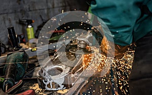 Man working with rotary angle grinder at workshop, closeup detail, orange sparks flying around