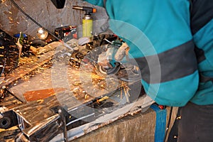 Man working with rotary angle grinder at workshop, closeup detail, orange sparks flying around