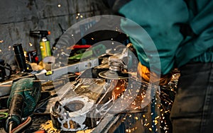 Man working with rotary angle grinder at workshop, closeup detail, orange sparks flying around