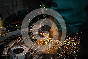 Man working with rotary angle grinder at workshop, closeup detail, orange sparks flying around