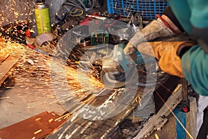 Man working with rotary angle grinder at workshop, closeup detail, orange sparks flying around