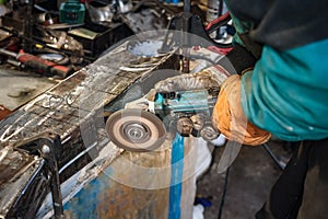 Man working with rotary angle grinder at workshop, closeup detail to hands holding the tool