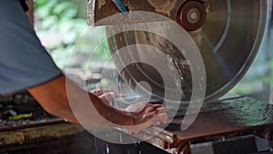 a man is working with a saw on a stone in close-up. A man cuts granite with an electric circular saw and pours water on