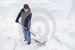 Man working shovel cleaning snow winter street in front of house after big snowstorm