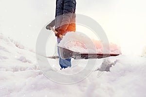 Man working shovel cleaning snow winter street in front of house after big snowstorm sunlight