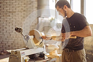 Man working at small wood lathe, an artisan carves piece of wood