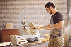 Man working at small wood lathe, an artisan carves piece of wood