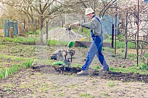 Man working in the spring garden with tiller machine