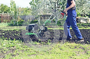 Man working in the spring garden with tiller machine