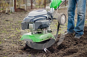 Man working in the spring garden with tiller machine