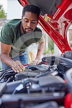 Man Working Under Hood Checking Car Engine Oil Level On Dipstick