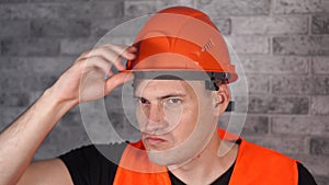 Man in working uniform turning orange protective hardhat