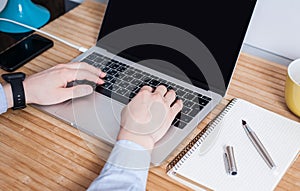 A man is working by using a laptop computer on vintage wooden table. Hand typing on a keyboard. Mockup