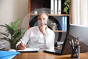 Man working virtually taking notes in online meeting