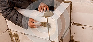 A man is working on a wall, applying a layer of cement