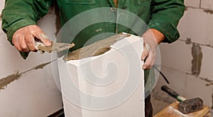 A man is working on a wall, applying a layer of cement