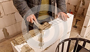 A man is working on a wall, applying a layer of cement