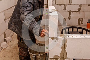 A man is working on a wall, using a level to make sure it is straight