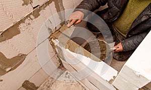 A man is working on a wall, using a trowel to apply cement