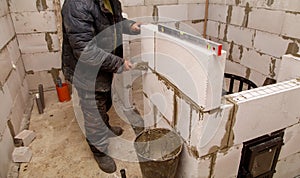 A man is working on a wall, using a trowel to apply mortar