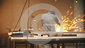 A man working in the welding workshop - grinder on the foreground